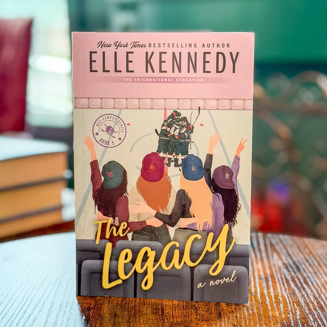 Book cover of 'The Legacy' by Elle Kennedy on a table with a blurred background