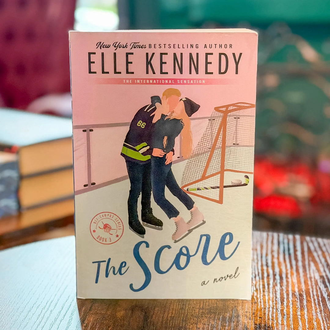Book titled 'The Score' by Elle Kennedy on a wooden surface with a blurred background