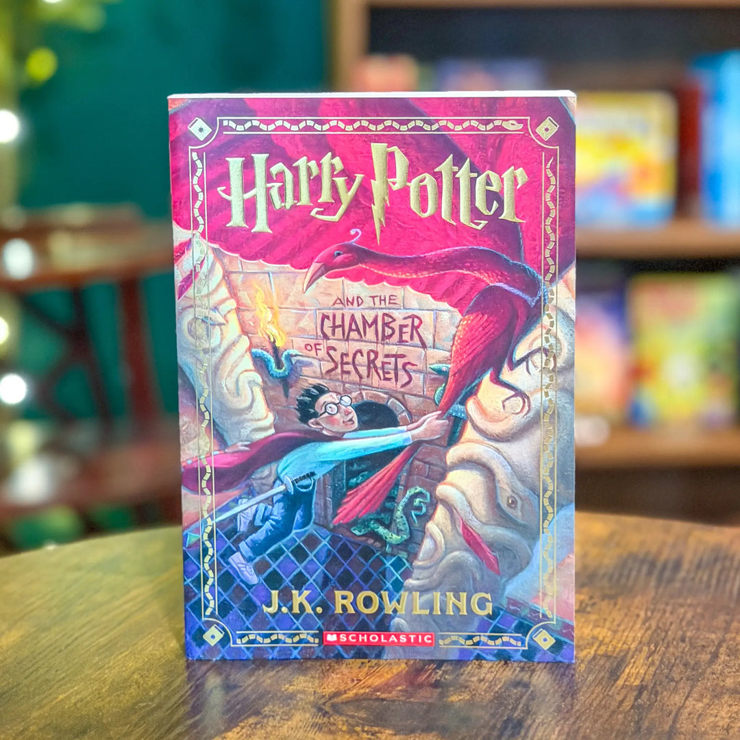 Book titled 'Harry Potter and the Chamber of Secrets' by J.K. Rowling on a wooden table with a blurred background.