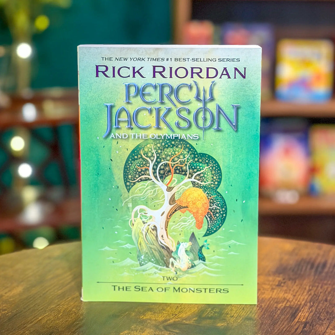Book titled 'Percy Jackson and the Olympians' by Rick Riordan on a wooden surface with a blurred background.