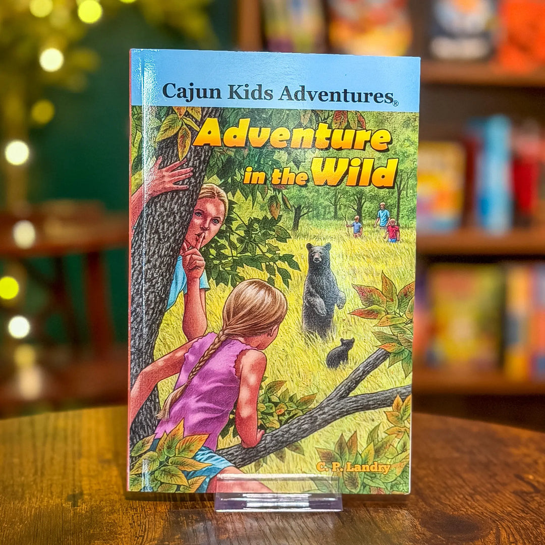 Book titled 'Adventure in the Wild' from 'Cajun Kids Adventures' series on a wooden surface with a blurred bookshelf background.
