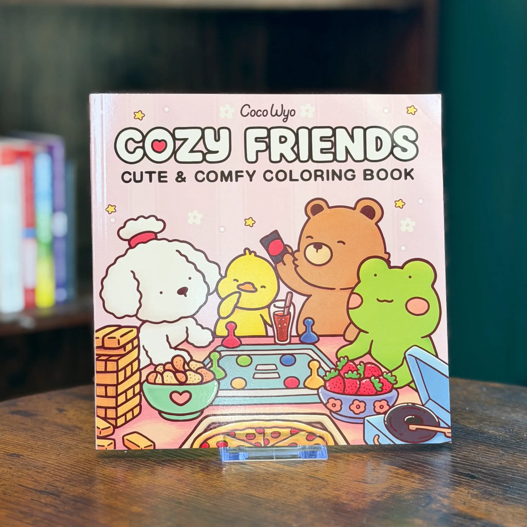 Coloring book titled 'Cozy Friends' with cartoon characters on a wooden surface.