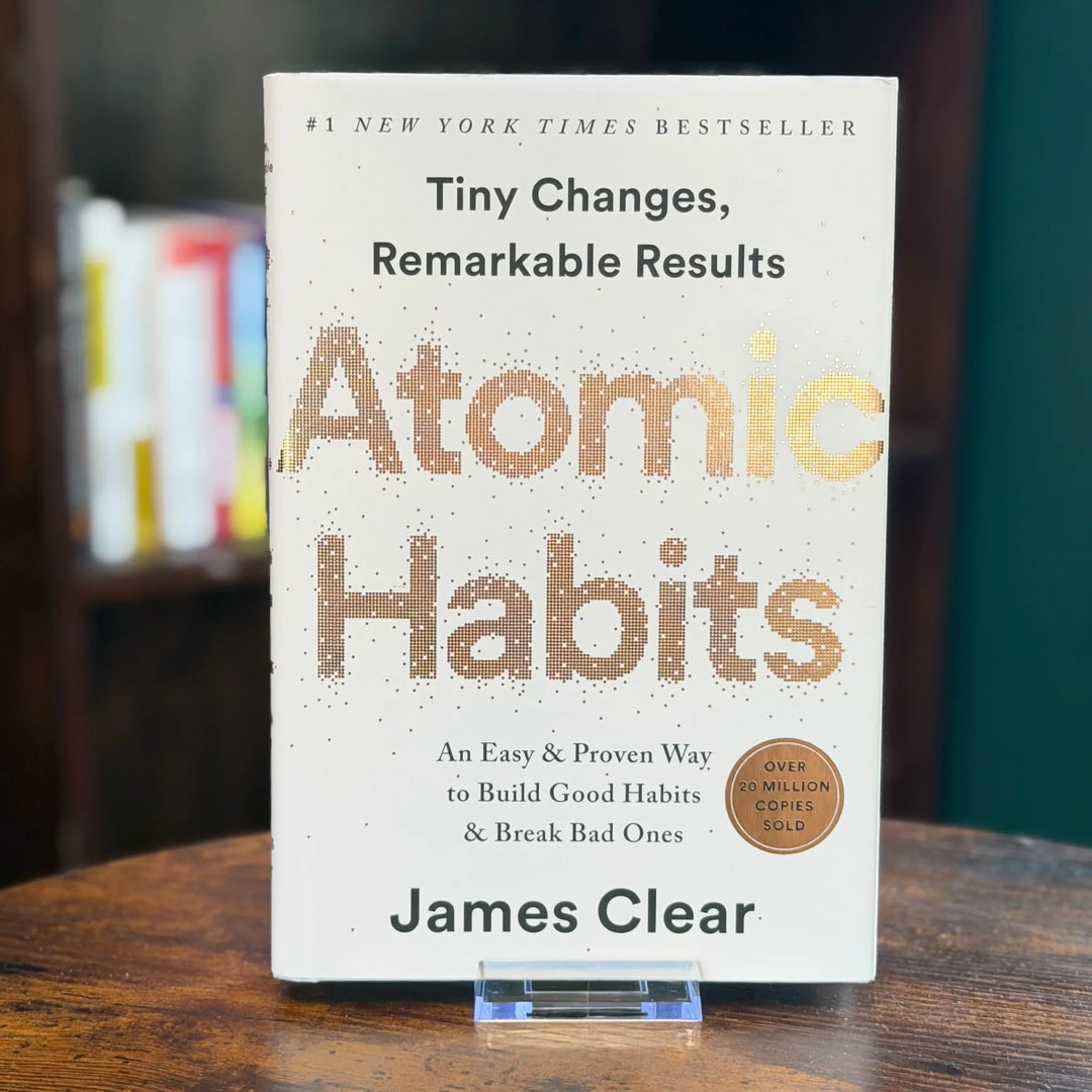 Book titled 'Atomic Habits' by James Clear on a wooden surface with a blurred background