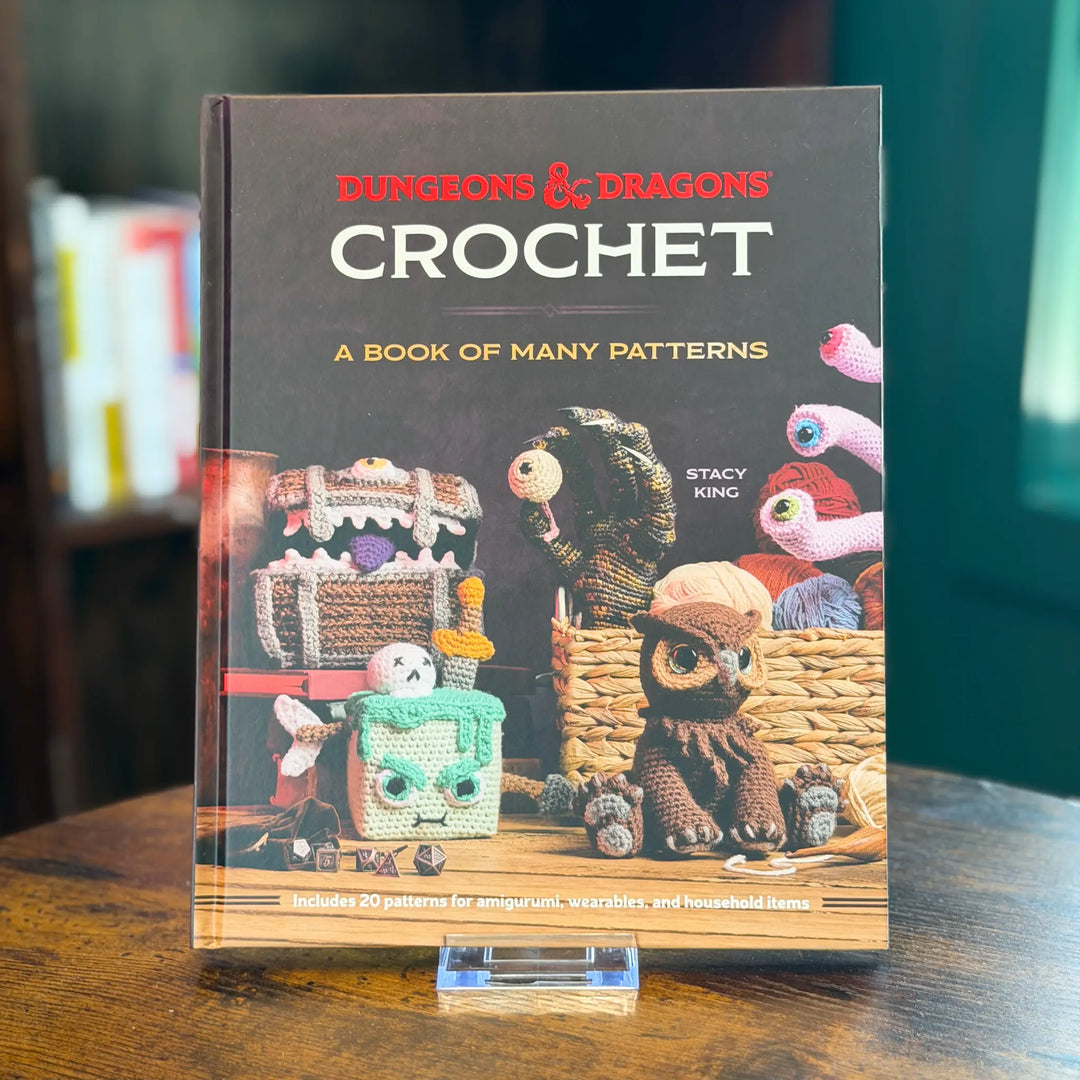 Book titled 'Dungeons & Dragons Crochet: A Book of Many Patterns' by Stacy King on a wooden surface.