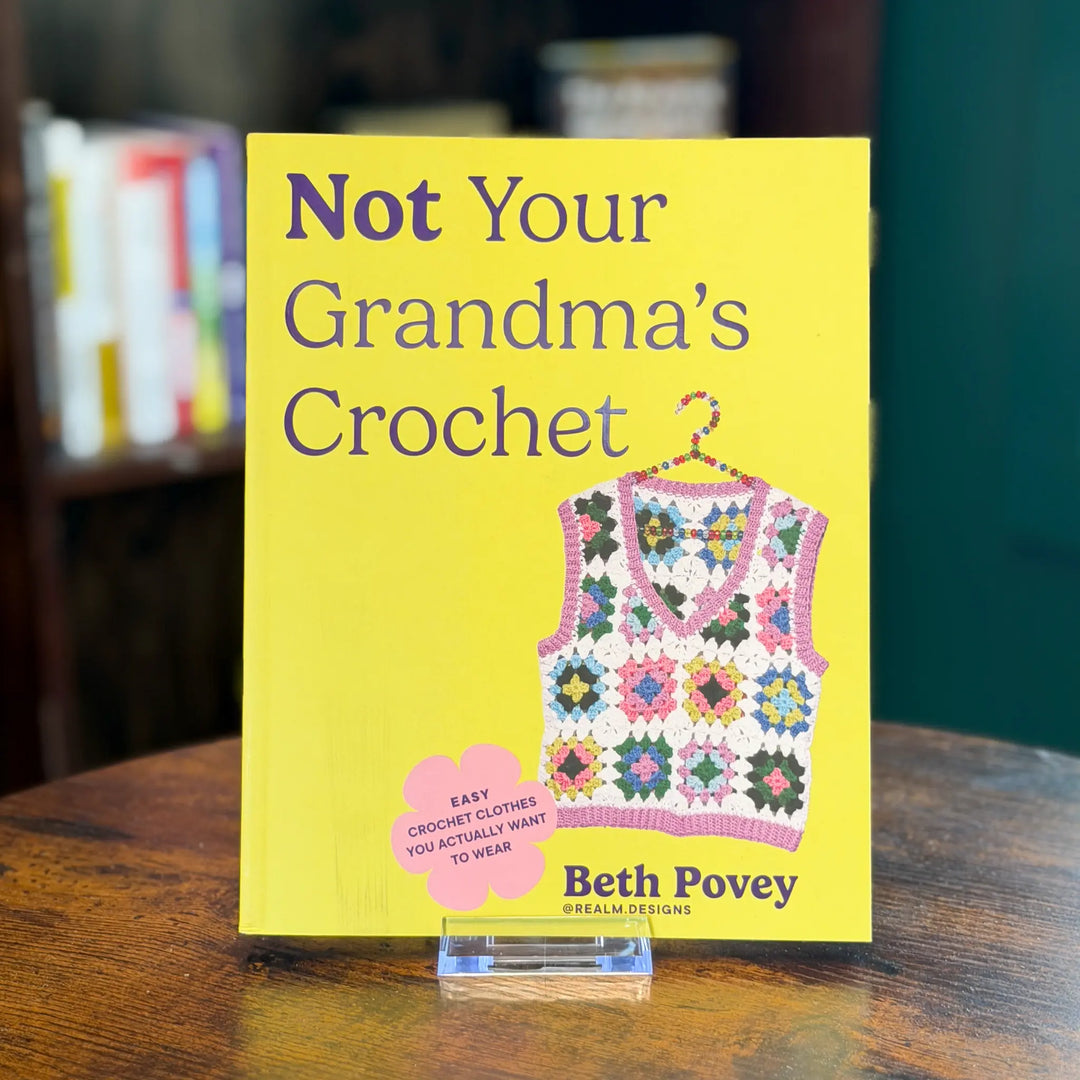 Book titled 'Not Your Grandma's Crochet' by Beth Povey on a wooden surface with a blurred background.