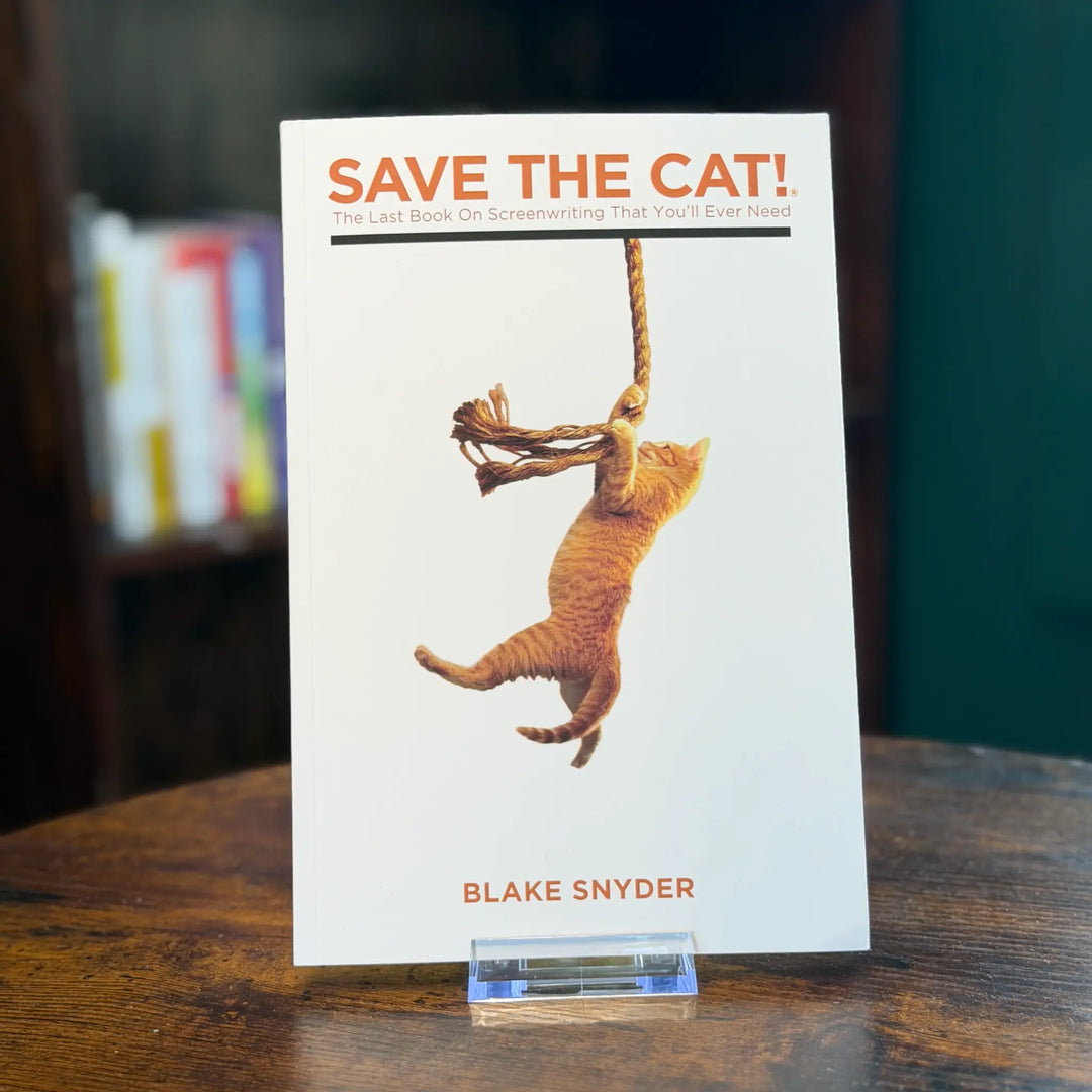 Book titled 'Save the Cat!' by Blake Snyder on a wooden surface with blurred bookshelf in the background.