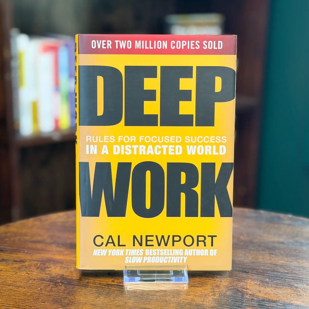 Book titled 'Deep Work' by Cal Newport on a wooden surface with a blurred bookshelf background.