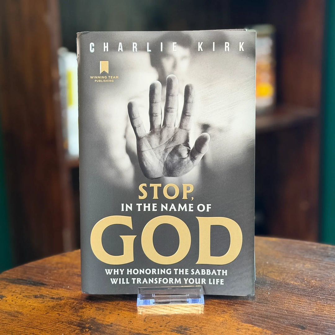 Book titled 'Stop, In the Name of God' by Charlie Kirk on a wooden surface.