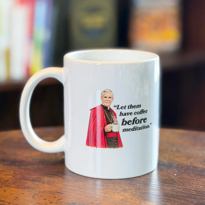 White mug with a graphic of a character holding a coffee cup and text on a wooden surface.