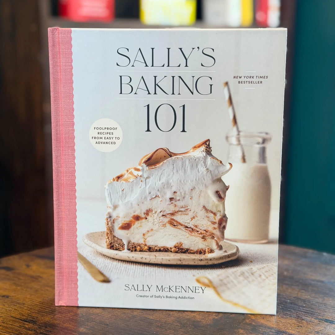 Book titled 'Sally's Baking 101' on a wooden surface with a blurred background