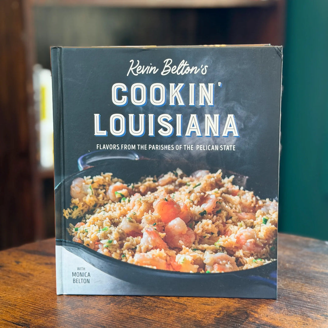 Cookbook titled 'Cookin' Louisiana' by Kevin Belton on a wooden surface.