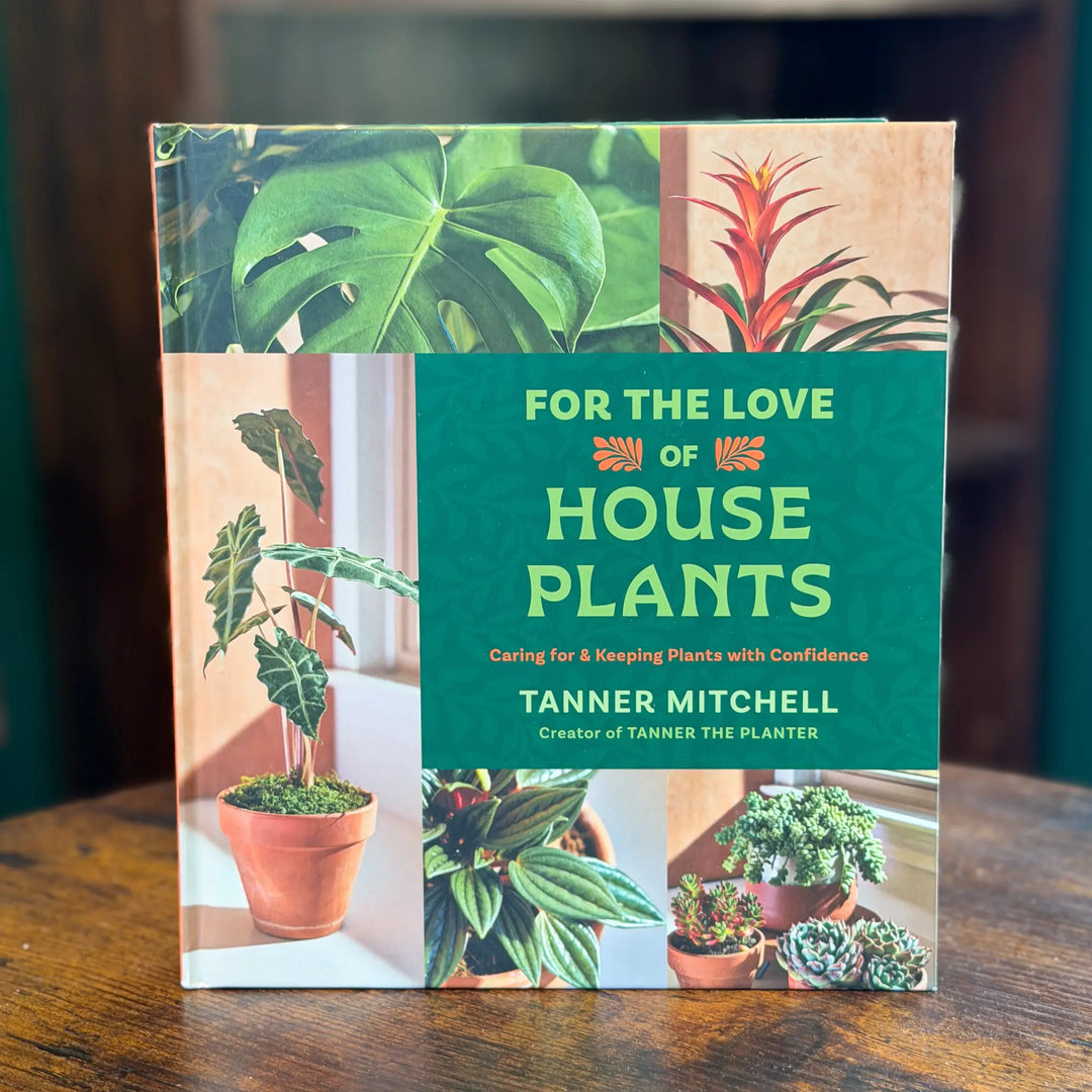 Book titled 'For the Love of House Plants' by Tanner Mitchell on a wooden surface.
