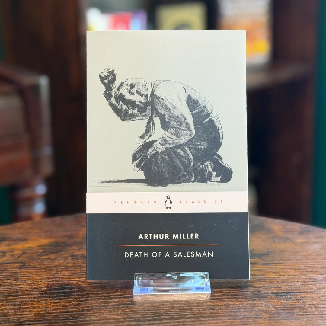 Book cover of 'Death of a Salesman' by Arthur Miller on a wooden table.