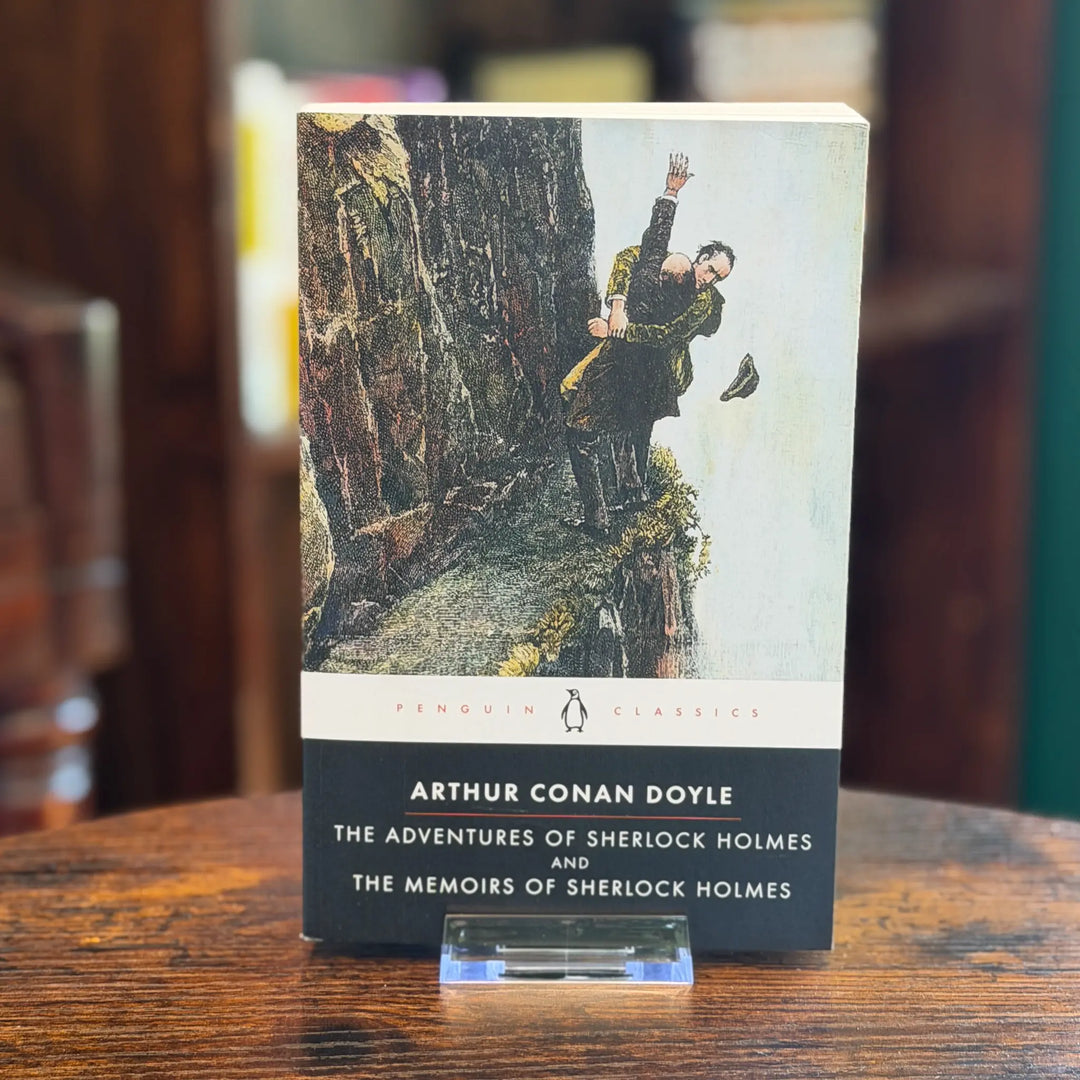Book titled 'The Adventures of Sherlock Holmes and The Memoirs of Sherlock Holmes' by Arthur Conan Doyle on a wooden surface.