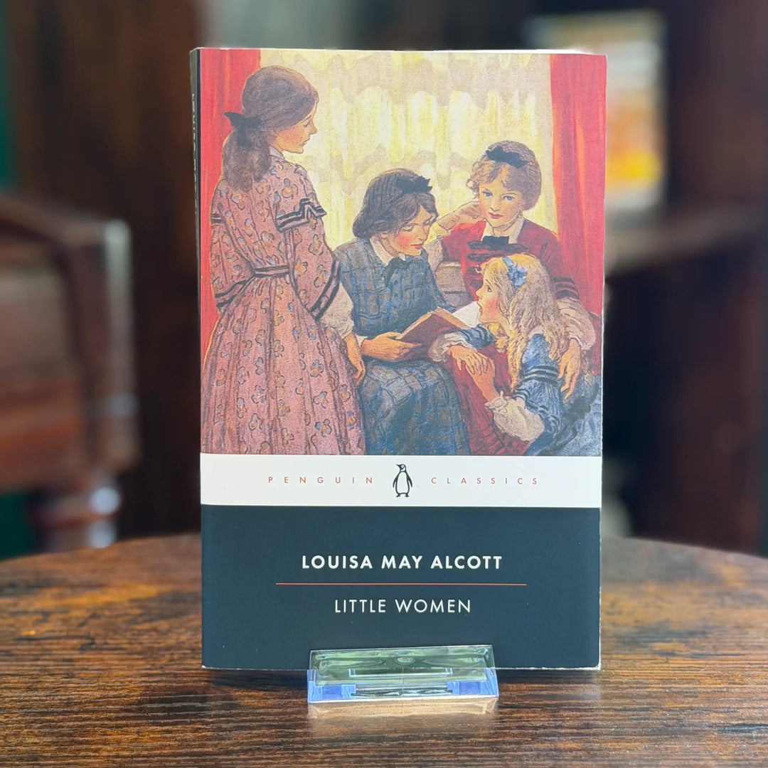 Book cover of 'Little Women' by Louisa May Alcott on a wooden surface.