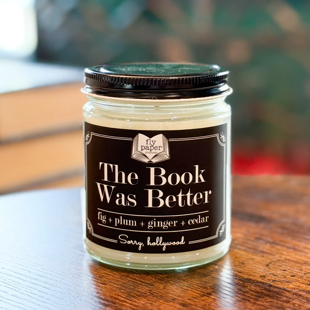 Jar of candle with 'The Book Was Better' label on a wooden surface