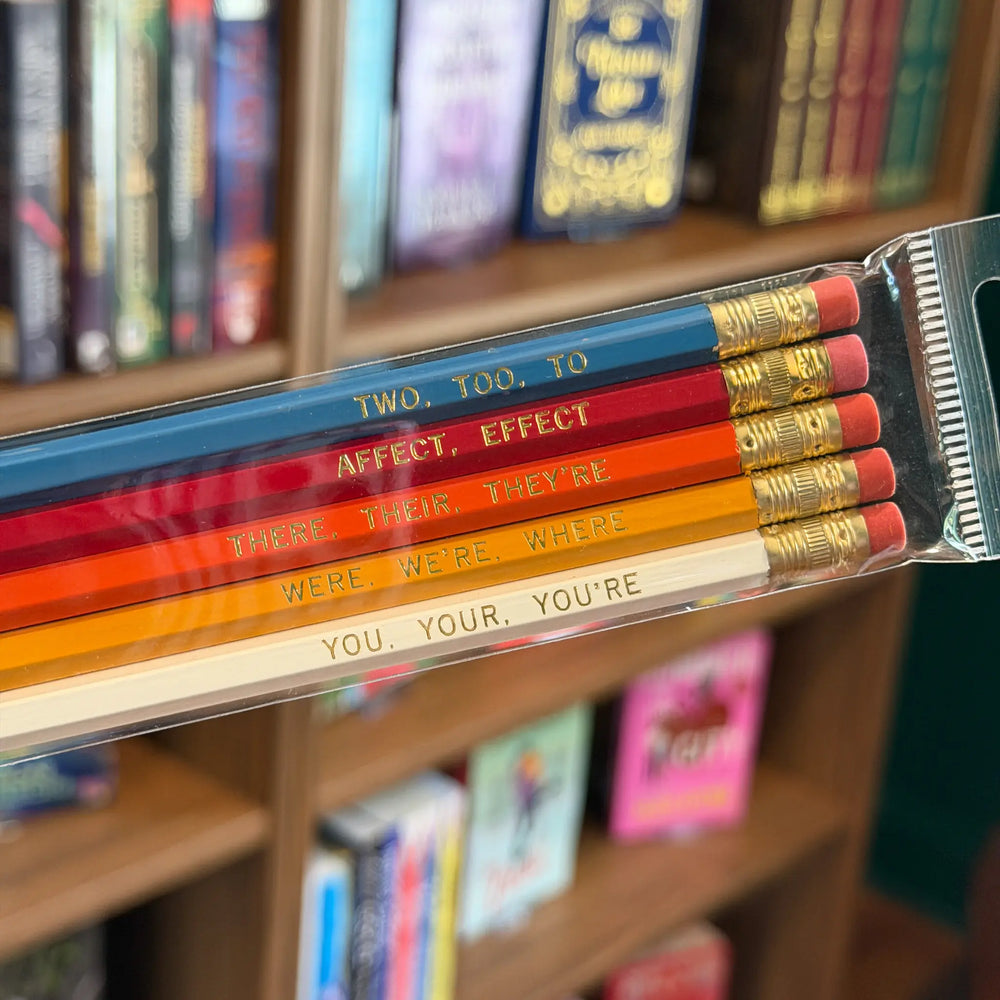 Packaged pencils with spelling corrections in front of a bookshelf