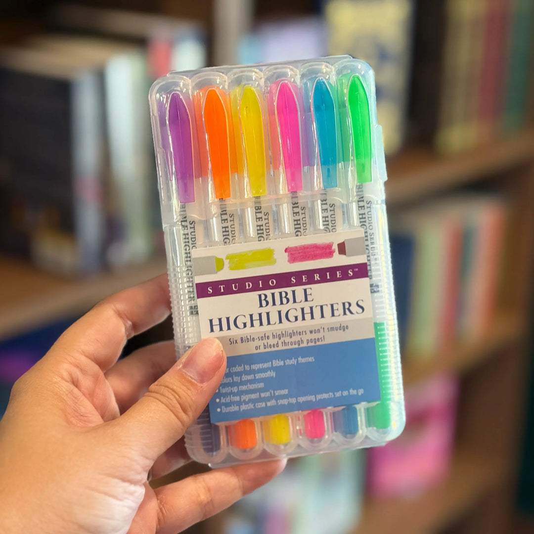 Pack of Bible highlighters held by a hand with a blurred bookshelf background