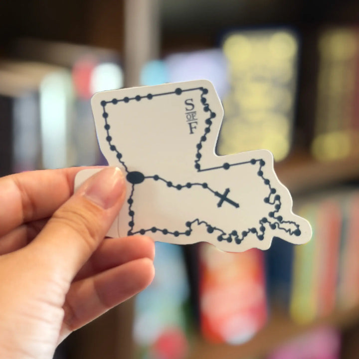 Hand holding a small map sticker of Louisiana with &