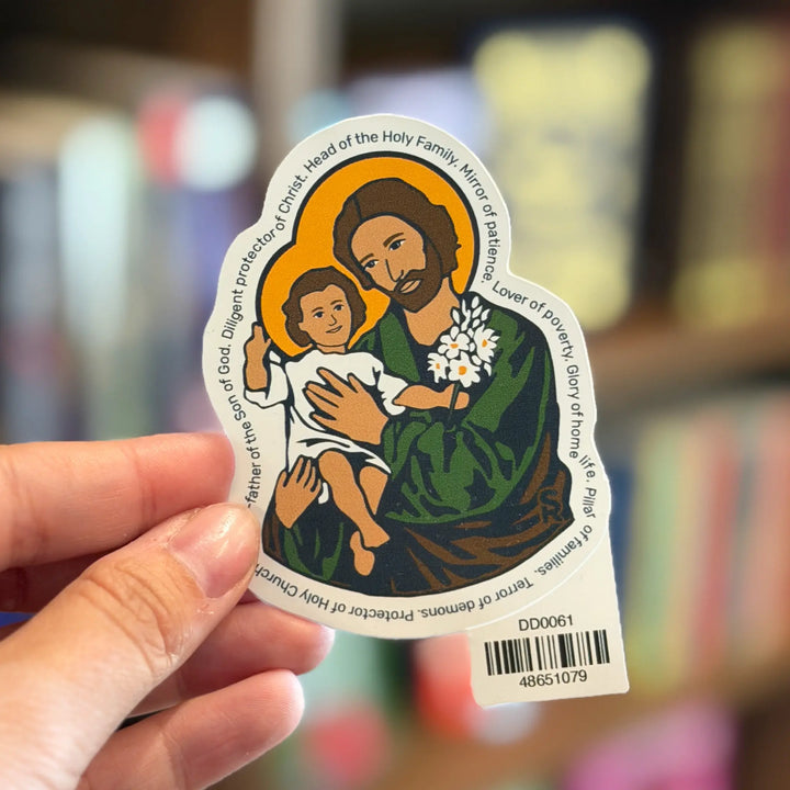 Sticker of a religious figure holding a child with text on a blurred bookshelf background