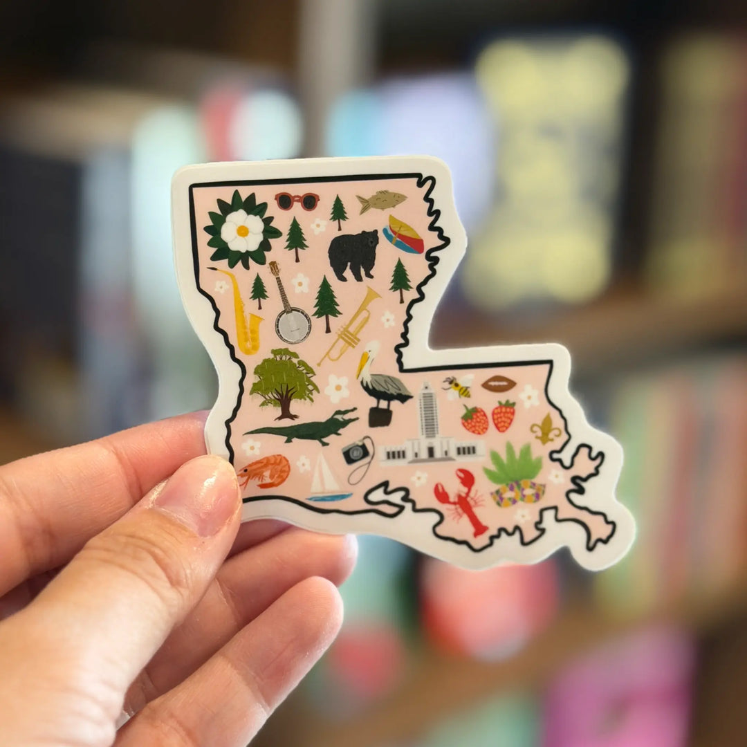 Sticker shaped like Louisiana with various symbols held by a hand against a blurred background.