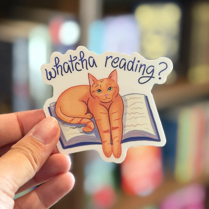 Sticker with a cat sitting on a book and &