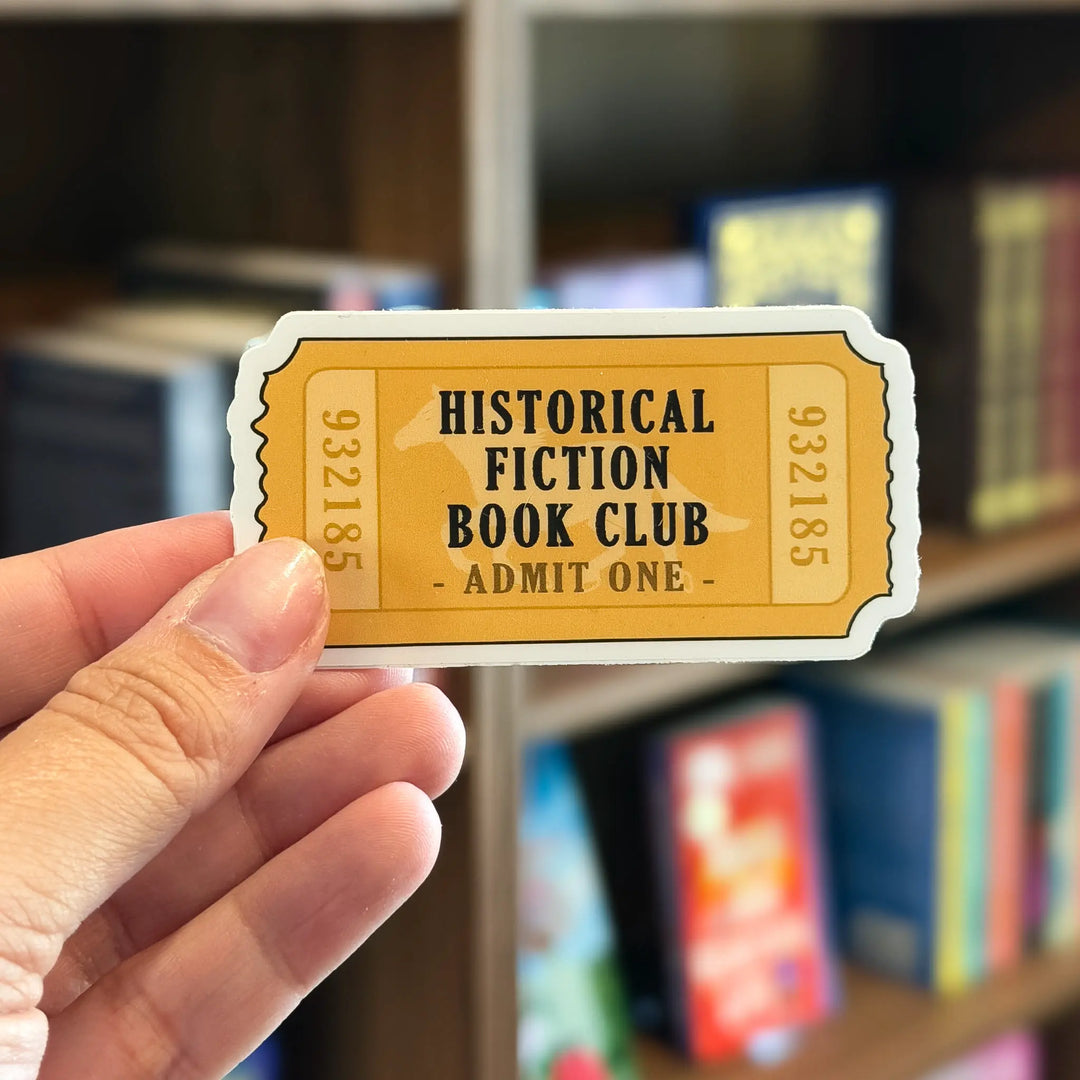 Hand holding a 'Historical Fiction Book Club' ticket with bookshelf in the background