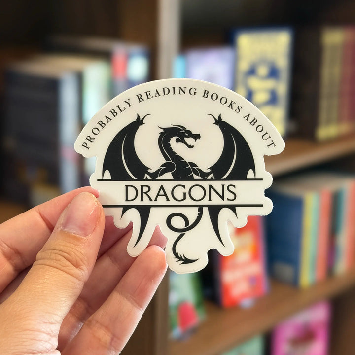 Sticker with dragon design held in front of a bookshelf