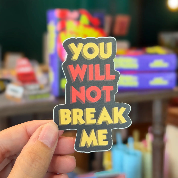 Hand holding a colorful sticker with text &
