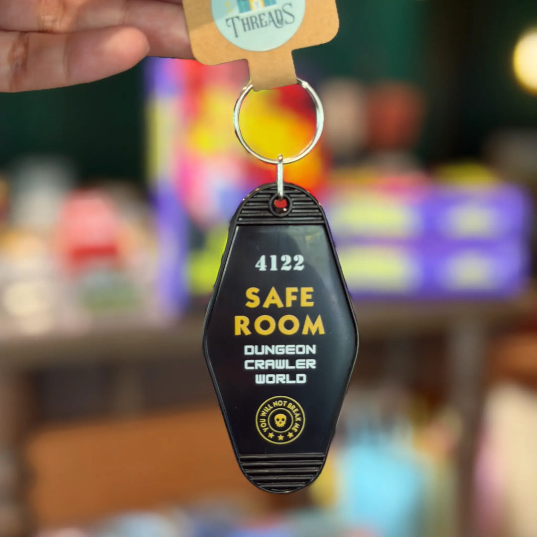 Keychain with 'Safe Room' text and number 4122, held against a colorful blurred background.