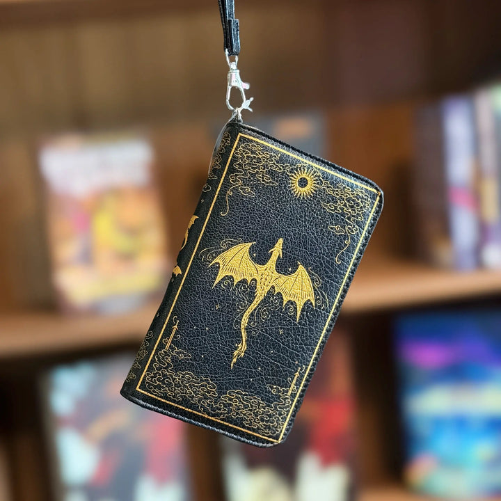 Black leather wallet with gold dragon design on a blurred bookshelf background