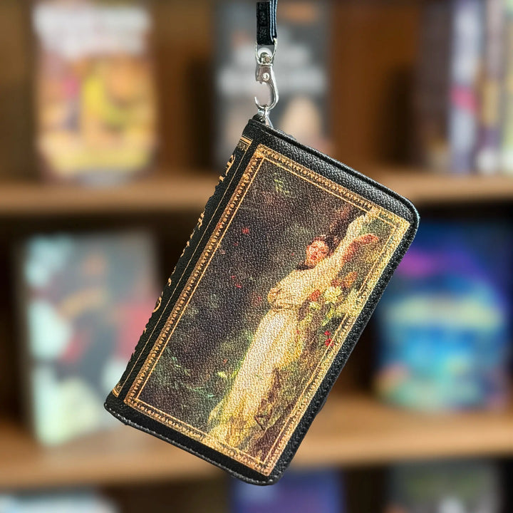 Decorative wallet with a printed design of a woman holding flowers, hanging against a blurred bookshelf background.