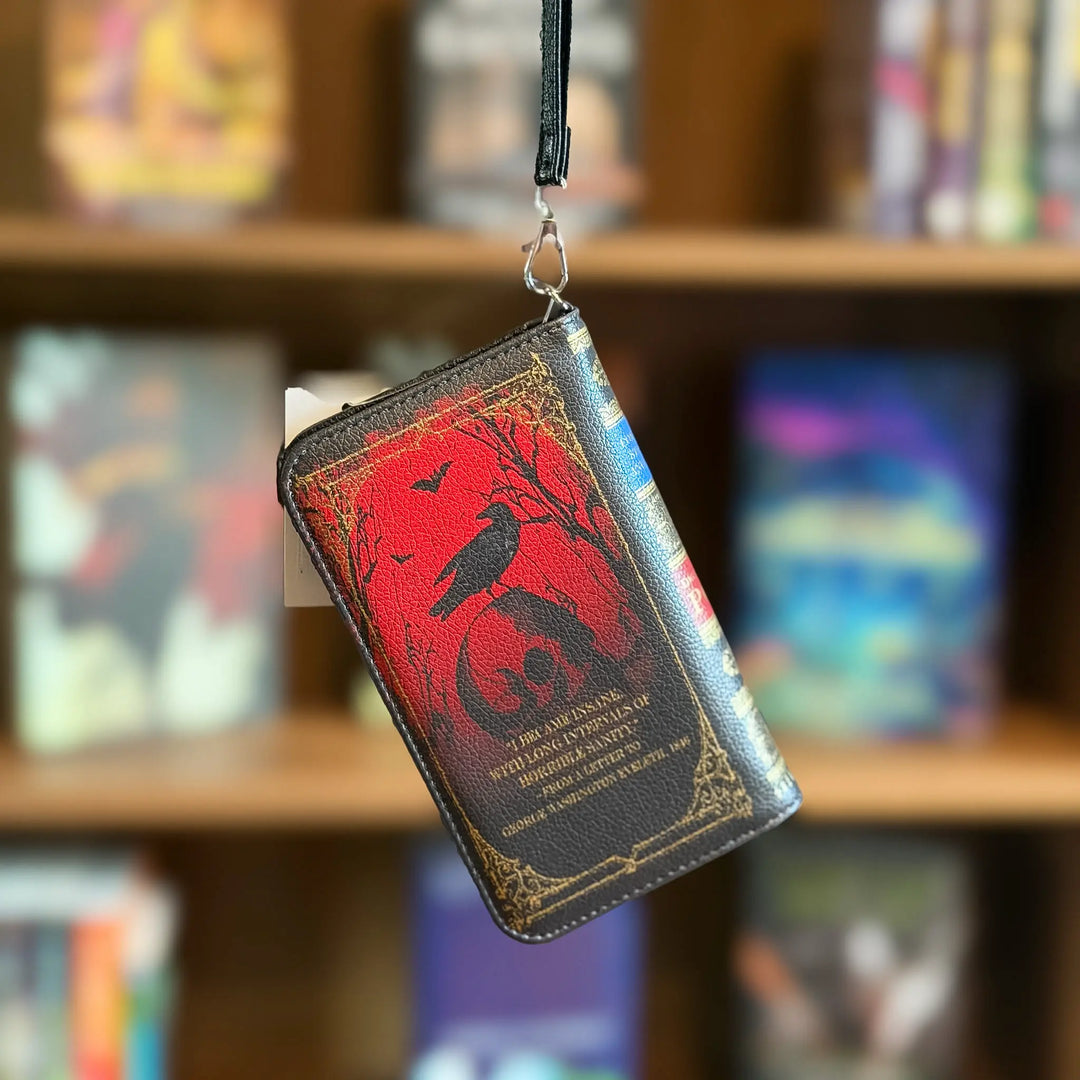 Book-shaped wallet with a red and black design hanging against a bookshelf background