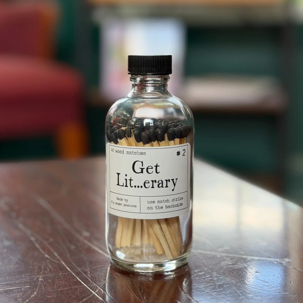 Bottle of matches labeled 'Get Lit...erary' on a wooden surface.