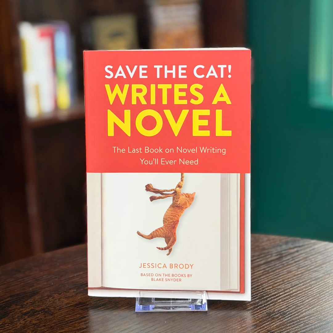 Book titled 'Save the Cat! Writes a Novel' on a wooden surface with a blurred bookshelf background.