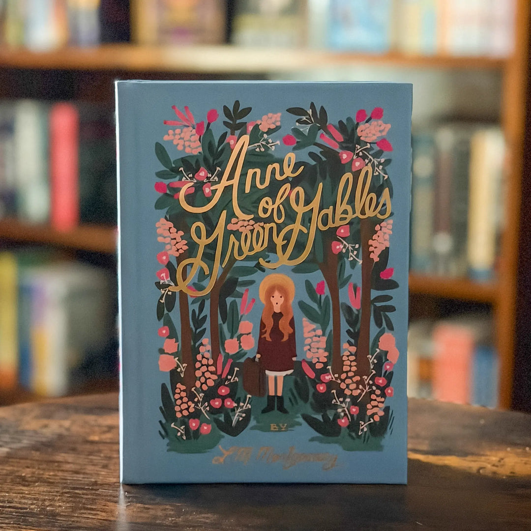 Book cover of 'Anne of Green Gables' with decorative elements on a wooden surface.