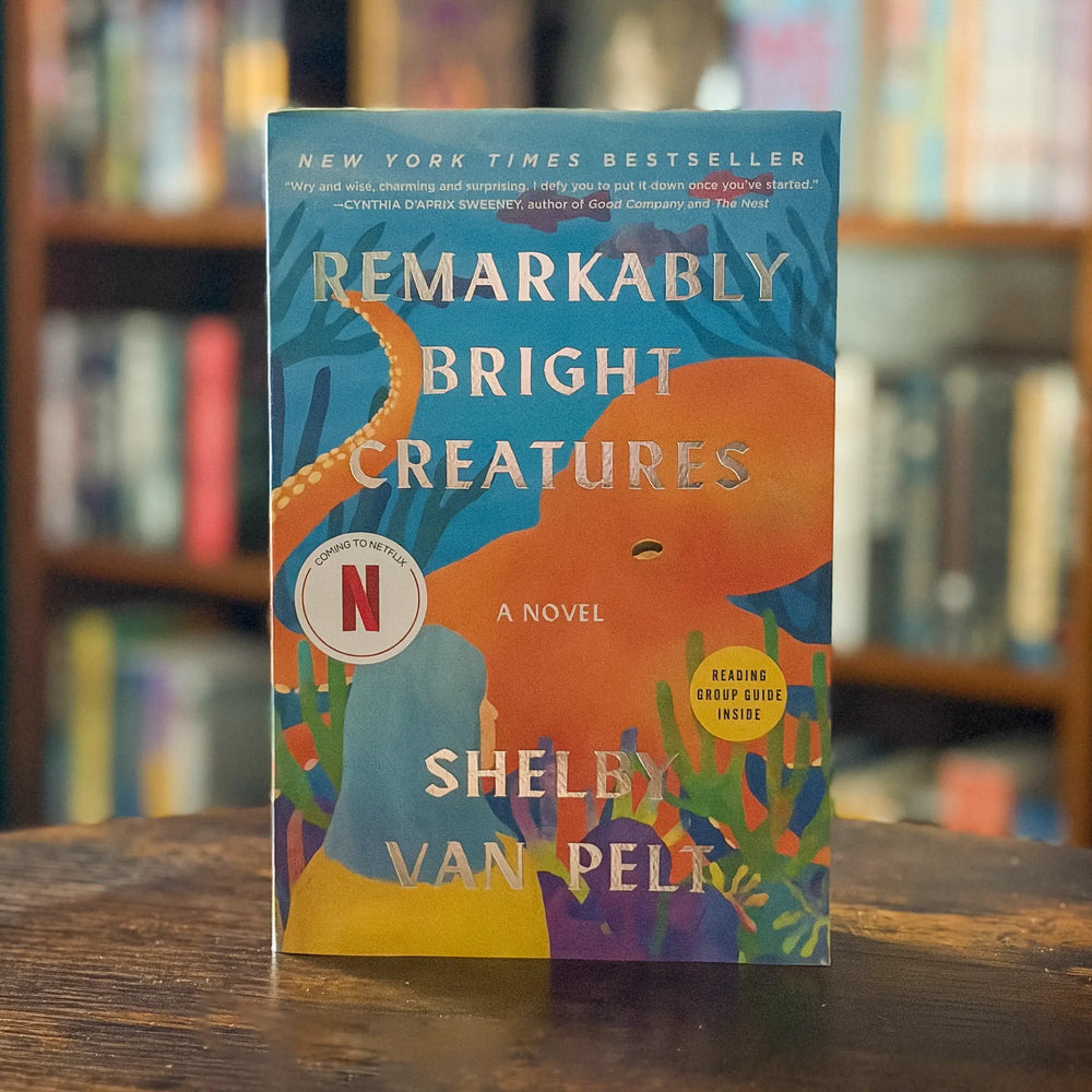Book titled 'Remarkably Bright Creatures' by Shelby Van Pelt on a wooden surface with a blurred bookshelf background.