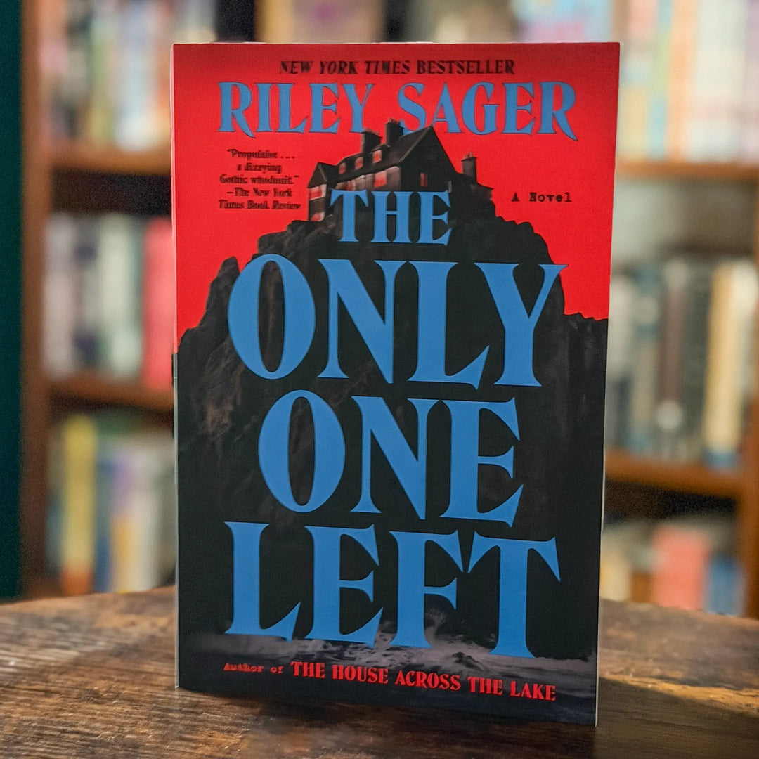 Book titled 'The Only One Left' by Riley Sager on a wooden surface with a blurred bookshelf background.