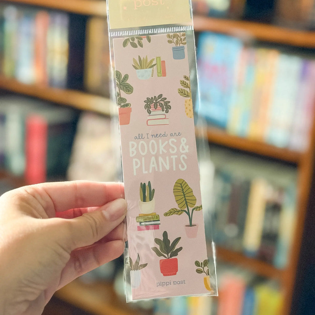 Bookmark with plant and book illustrations held in front of a bookshelf.