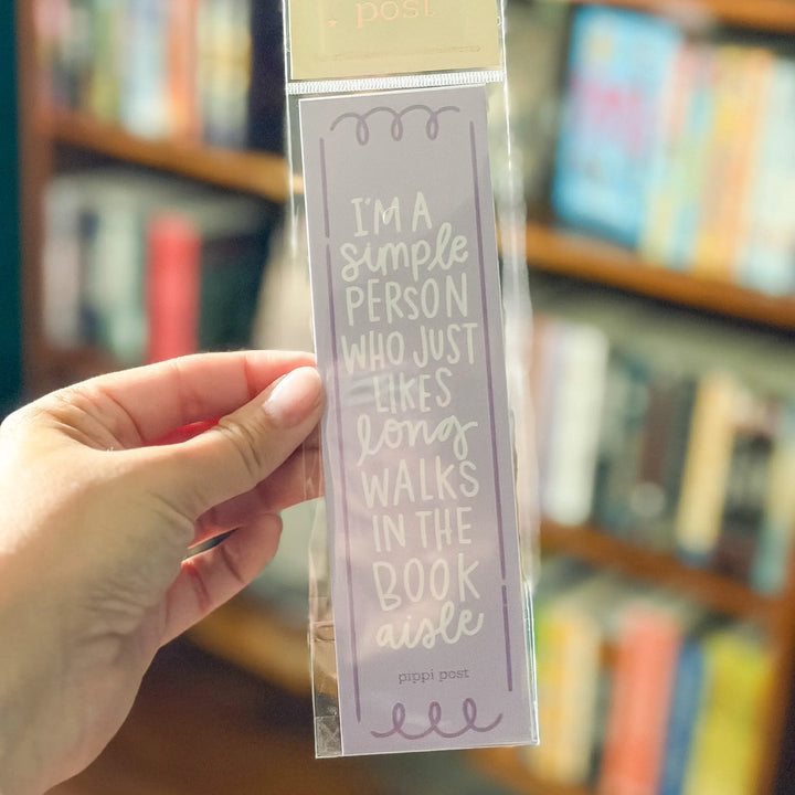 Hand holding a clear bookmark with text in front of a bookshelf.