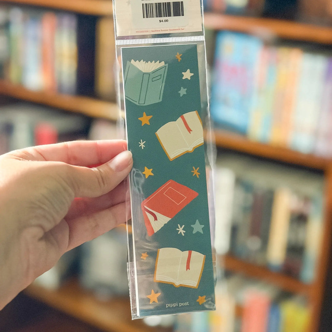 Packaged bookmark with book illustrations held in front of a bookshelf.