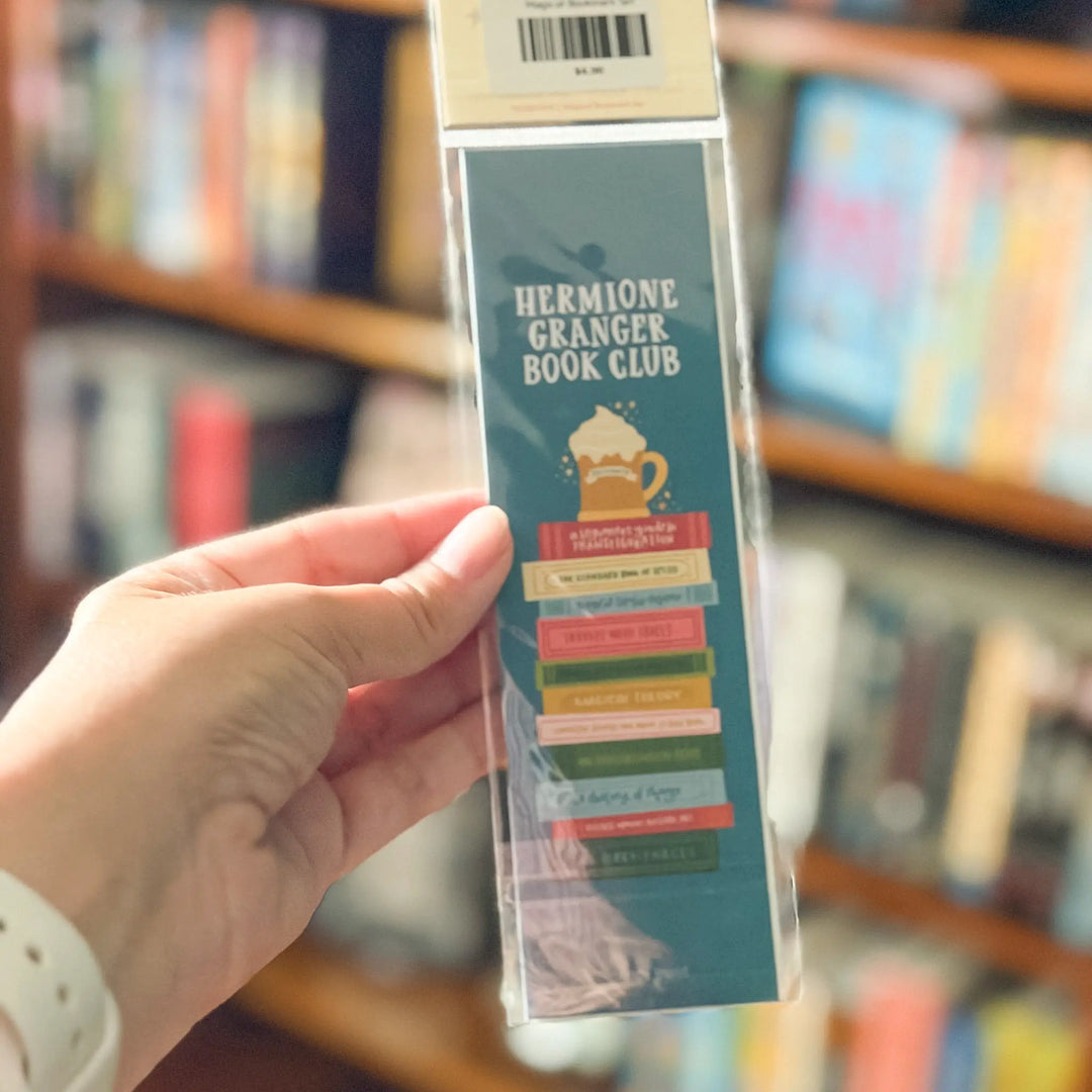 Hand holding a bookmark with bookshelf in the background