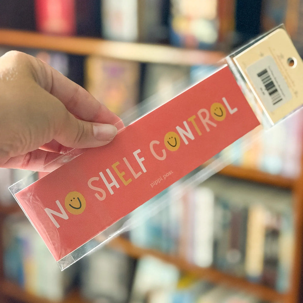 Hand holding a product with 'No Shelf Control' packaging in front of a blurred bookshelf background