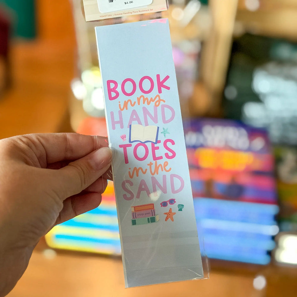 Hand holding a colorful bookmark with text and graphics against a blurred background