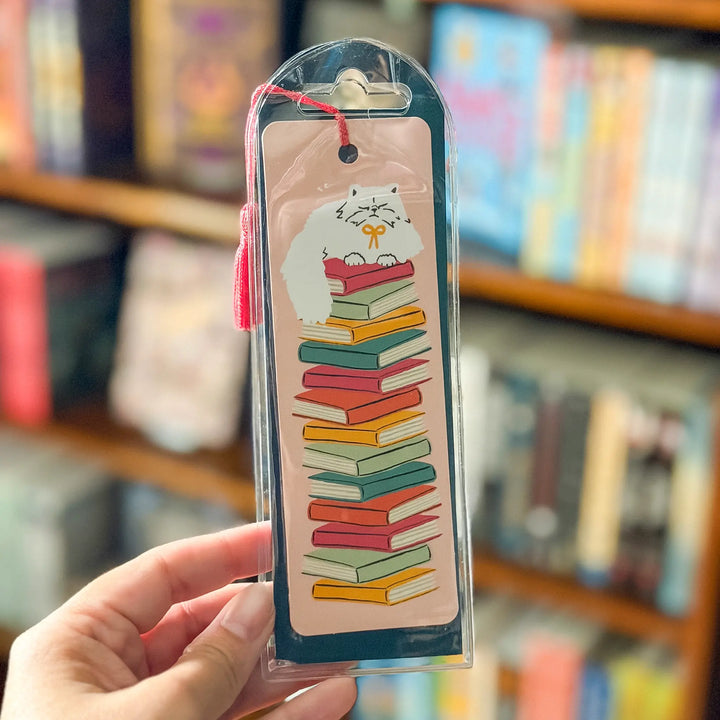 Bookmark with a cat on books design held in front of a bookshelf.