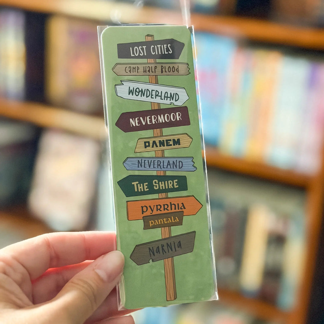 Hand holding a green bookmark with text against a blurred bookshelf background