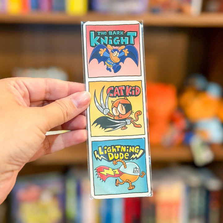 Hand holding a colorful packaging with cartoon characters against a blurred toy store background