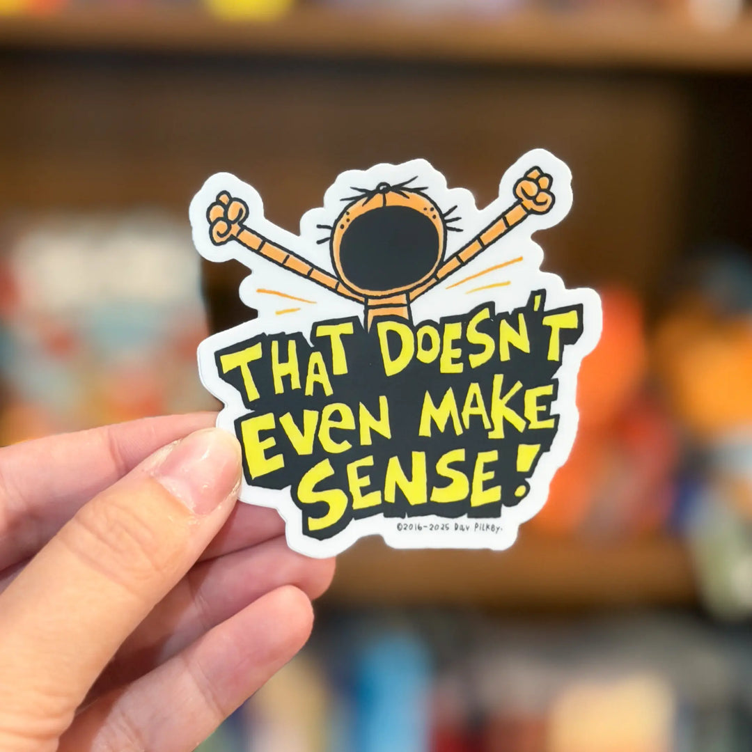 Hand holding a sticker with a cartoon character and text 'That doesn't even make sense!' against a blurred background.
