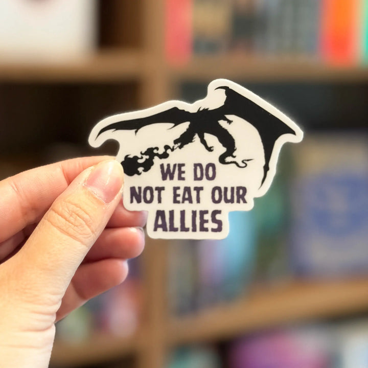 Hand holding a sticker with a dragon design and text &