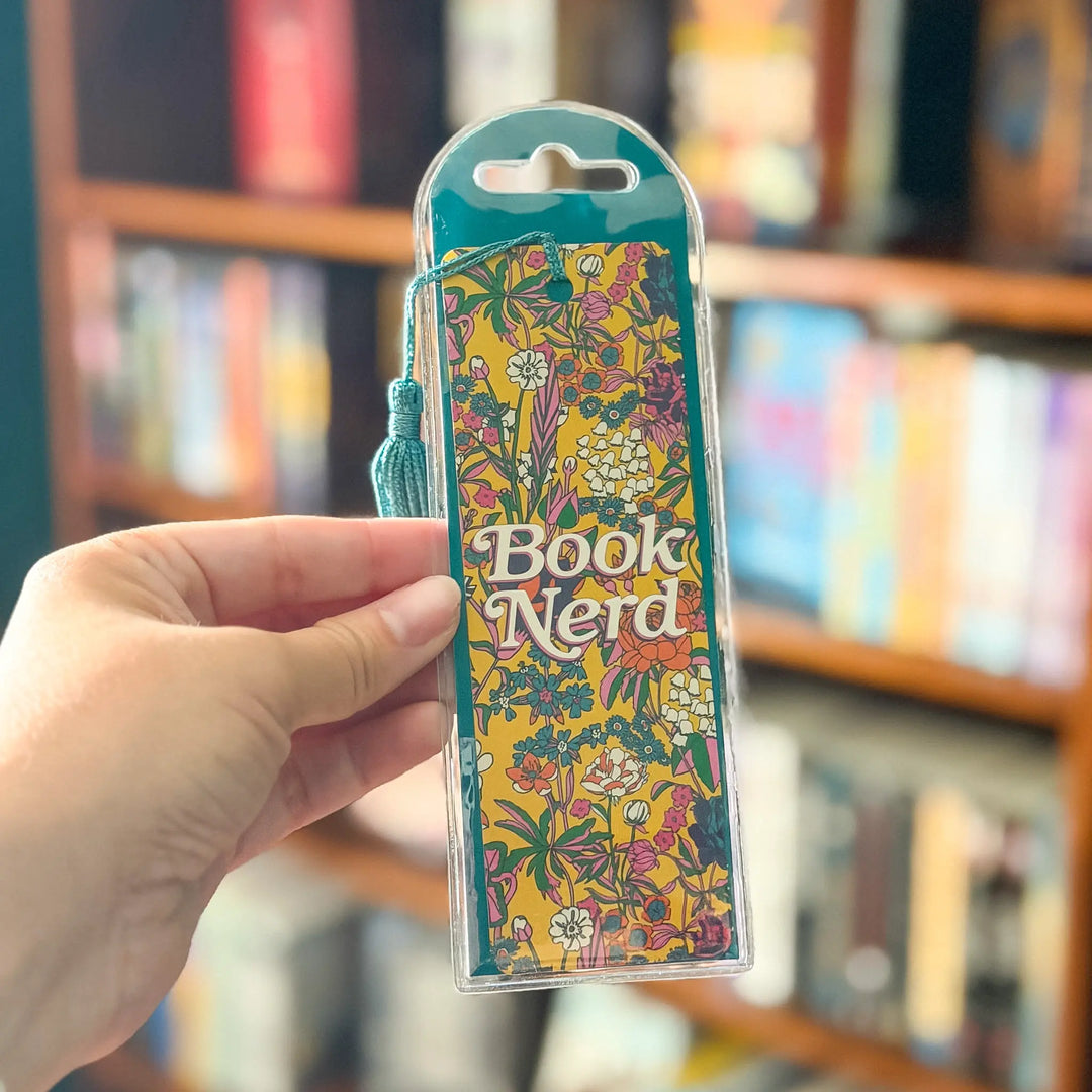 Colorful bookmark with 'Book Nerd' text held by a hand against a blurred bookshelf background